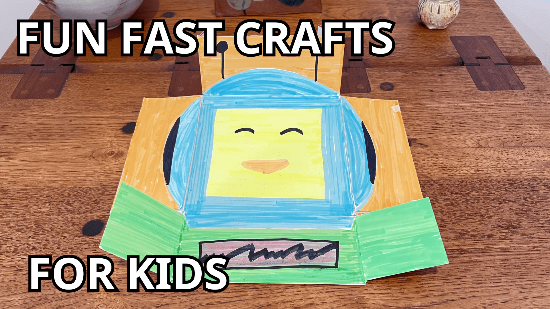The text "Fun Fast Crafts for Kids" is shown. A photo has a drawn robot face with orange, green, and blue colors on a cardboard snack box.